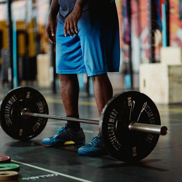 Focused man lifting weights with proper form in a bright space.